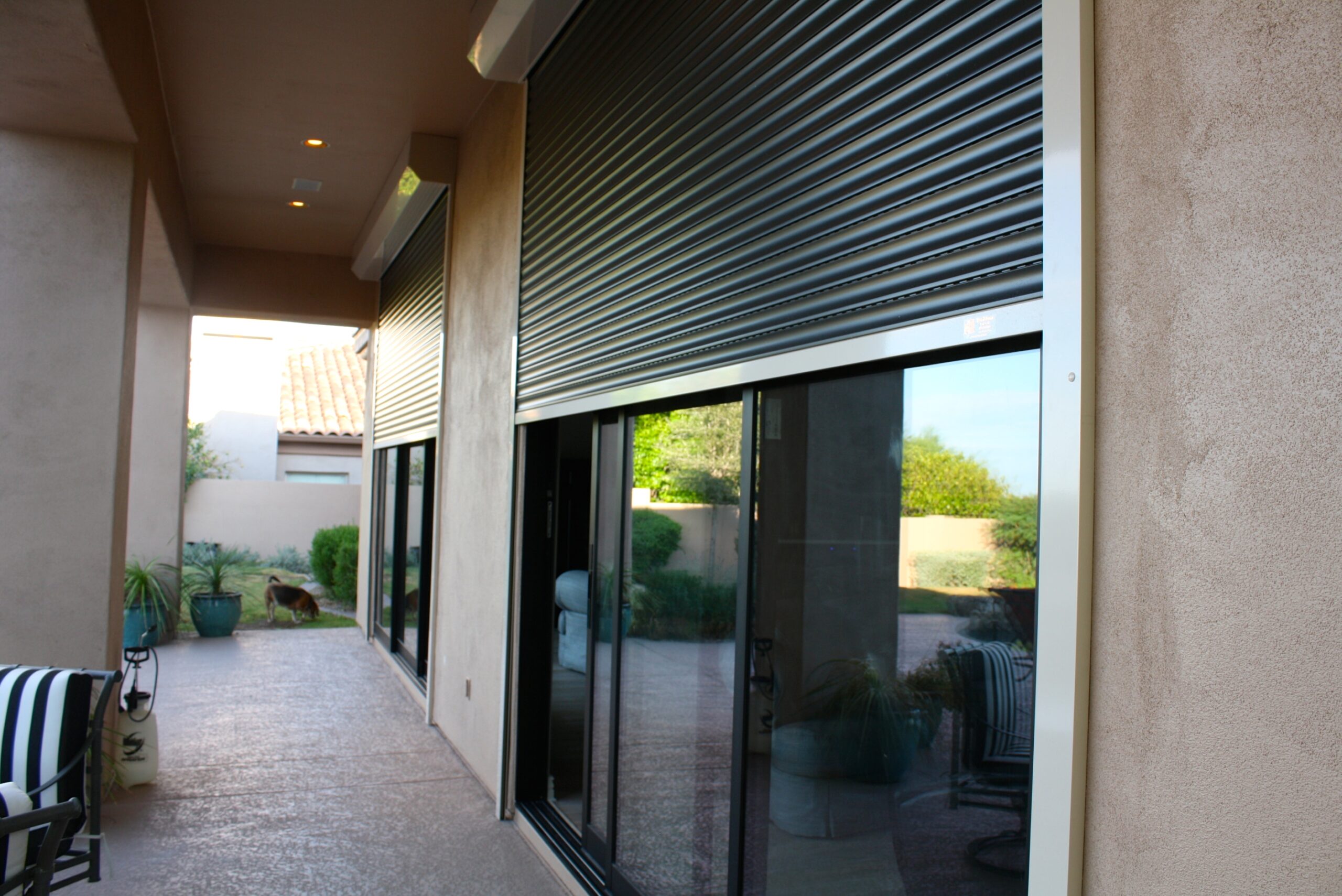 An image showing a halfway opened rolling shutters installed outside of a home's glass doors