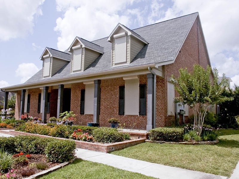 Two-story brick home with white motorized rolling shutters protecting upper windows that would otherwise be hard to reach