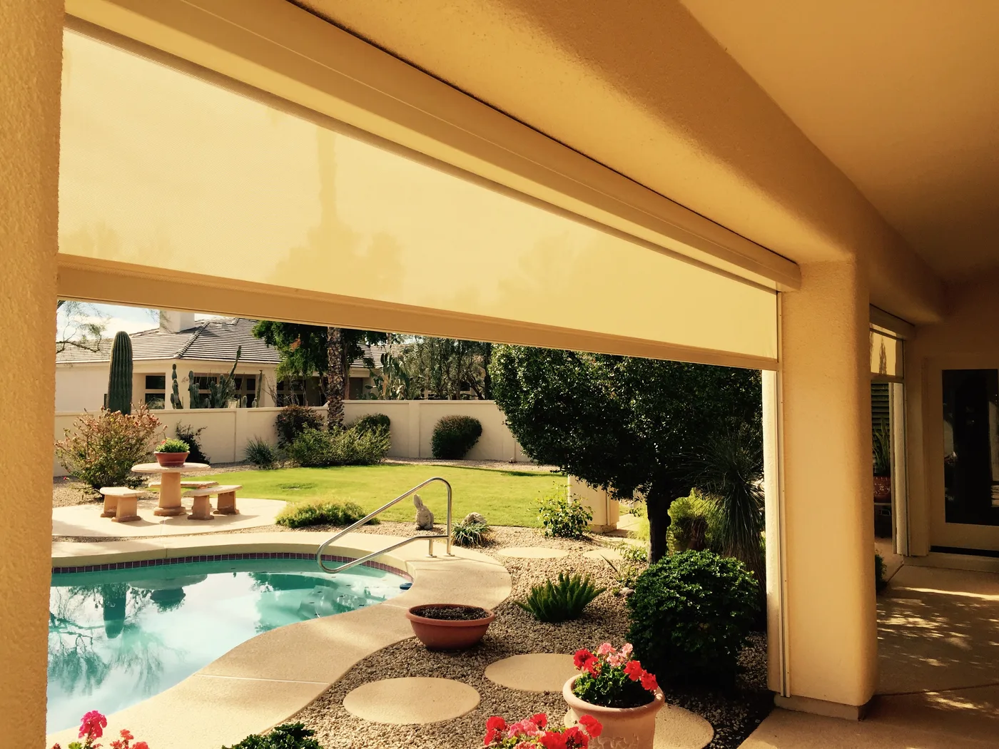 Cream retractable patio screen partially lowered over a Phoenix backyard pool patio, financed on the 120-month plan