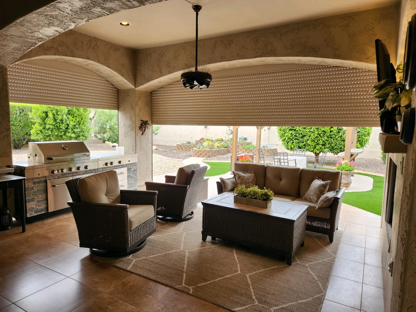 Tan rolling shutters partially lowered over the arched openings of a Phoenix outdoor living room, financed on the 180-month plan