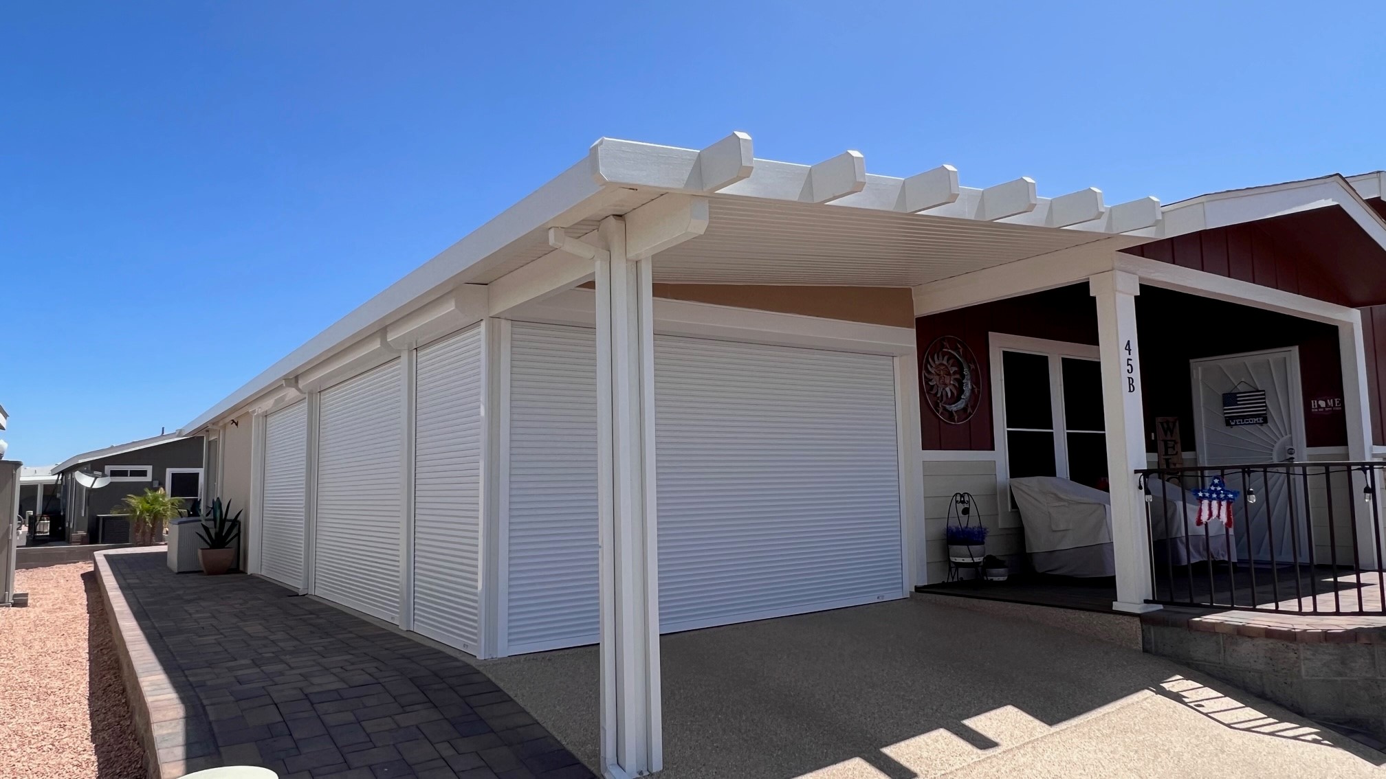 White rolling shutter curtains closed across the full width of a covered carport opening on an Arizona home