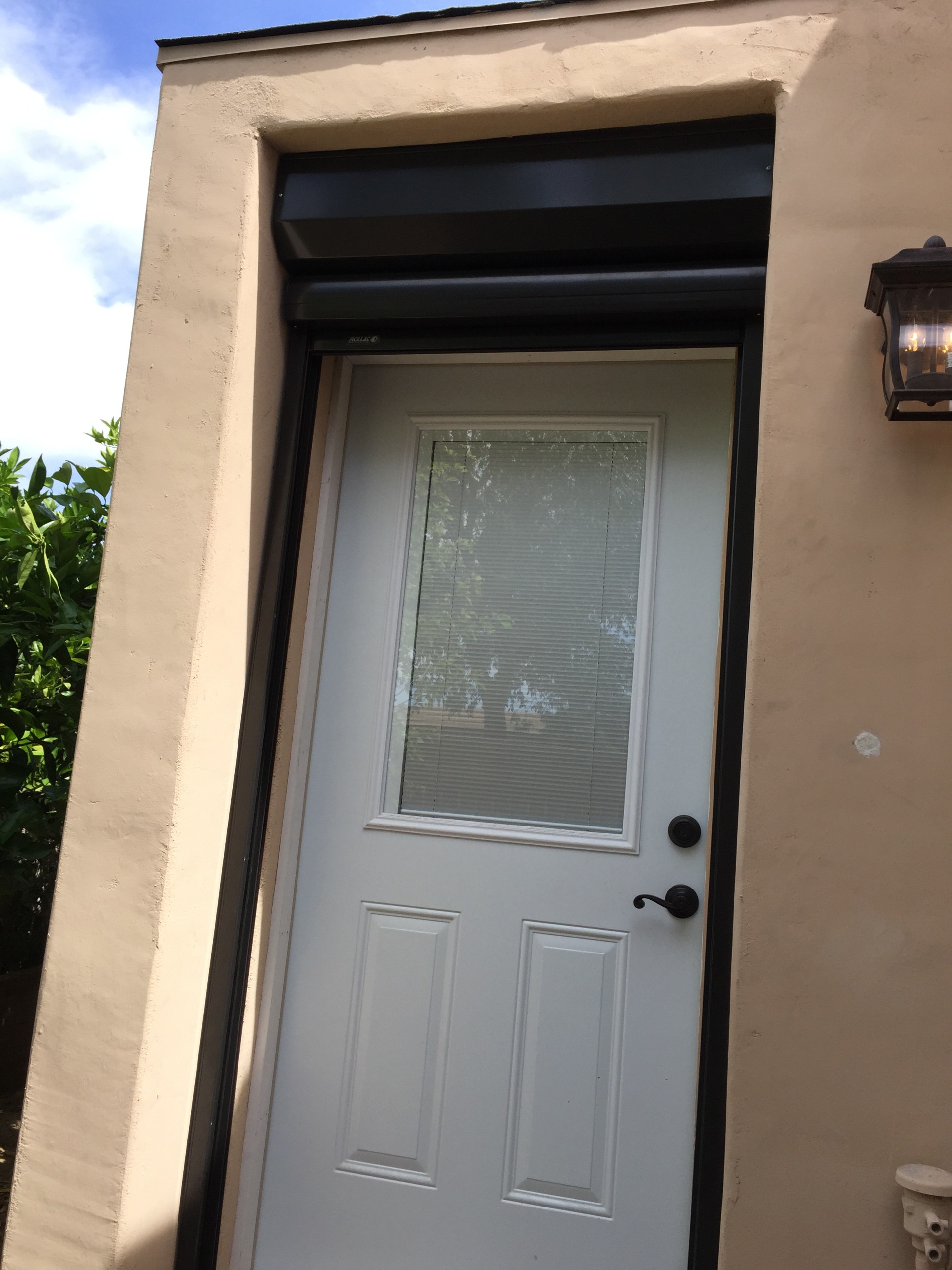 A side entry door on a Metro Phoenix home with a rolling shutter box mounted above the opening and the curtain rolled up inside it