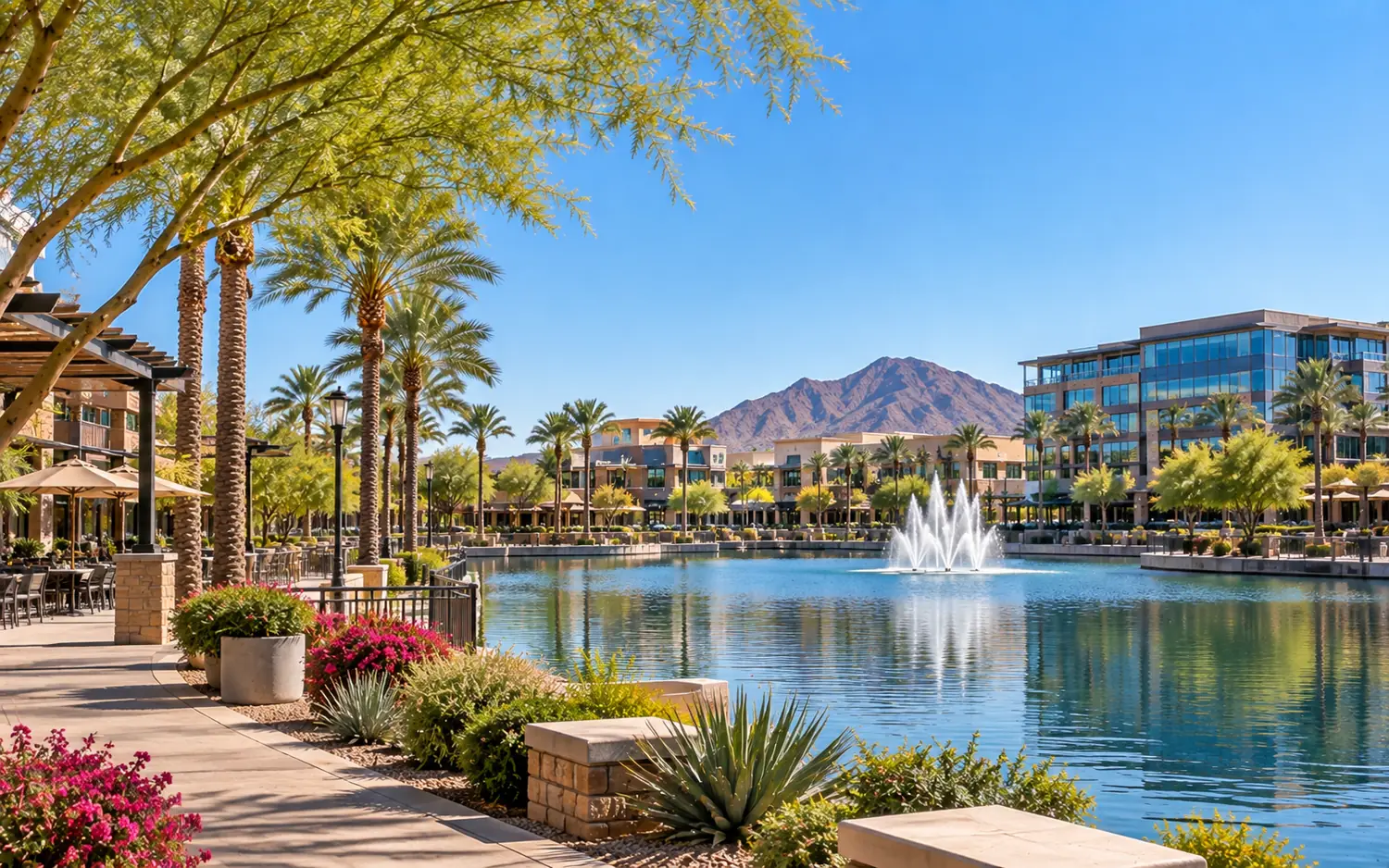 Lake with a fountain, palm trees, and office buildings in Chandler, Arizona, with a mountain under a clear blue sky