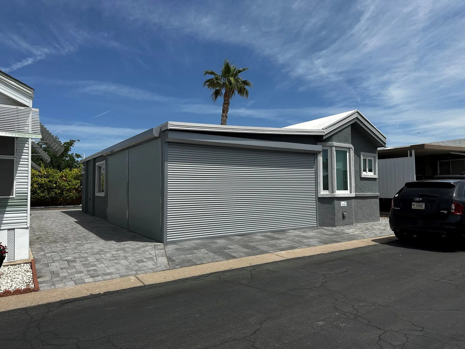 Grey rolling shutters closed across a carport and side opening on an Arizona home under a clear midday sky
