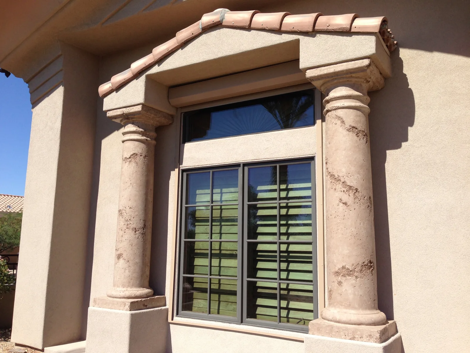 Sun striking an unshaded window on a Metro Phoenix home, with only interior shutters behind the glass