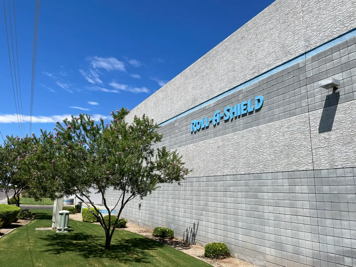 Roll-A-Shield facility exterior with the company name on the wall under a blue sky