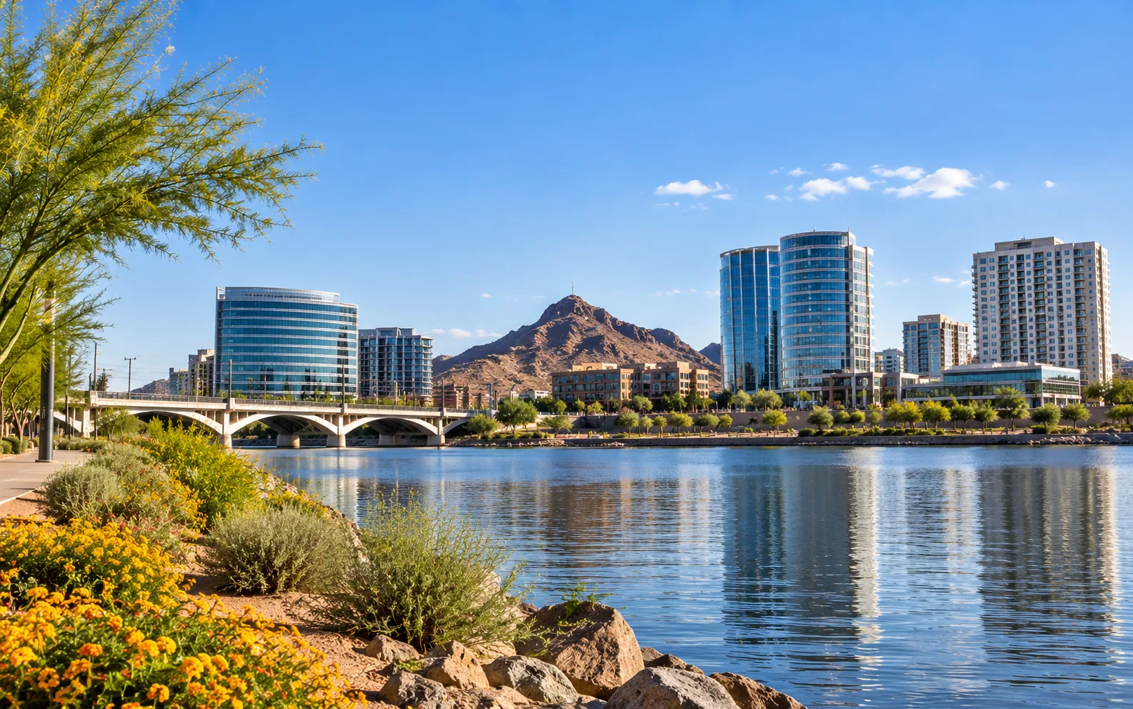 Metro Phoenix city skyline and a desert peak reflected in a lake on a clear day